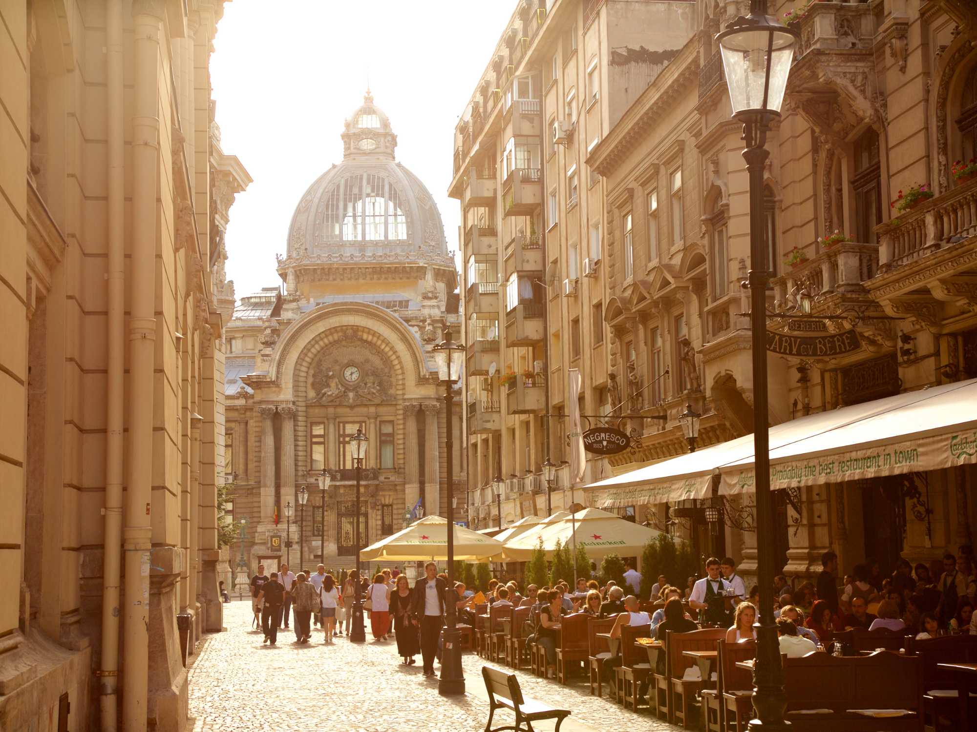 A street filled with people sitting in cafe gardens