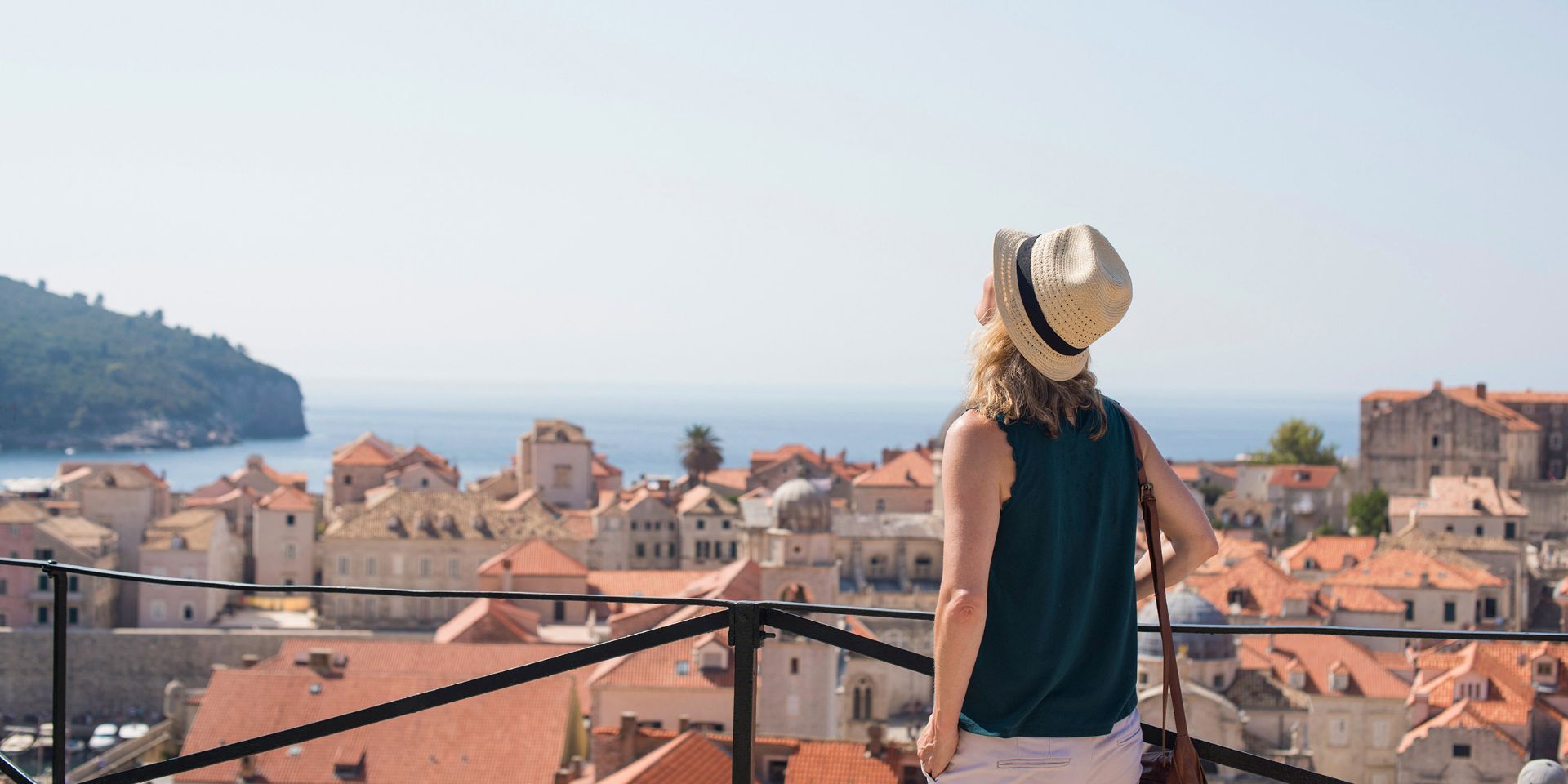 A woman wearing a hat standing on a balcony in Croatia