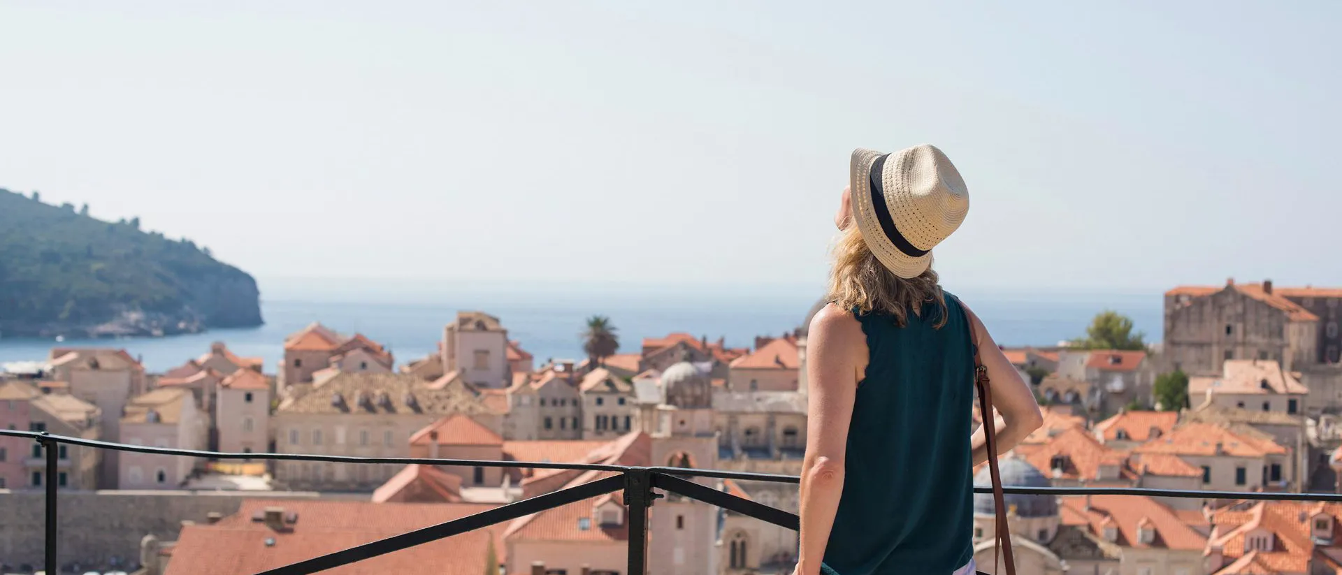 A woman wearing a hat standing on a balcony in Croatia