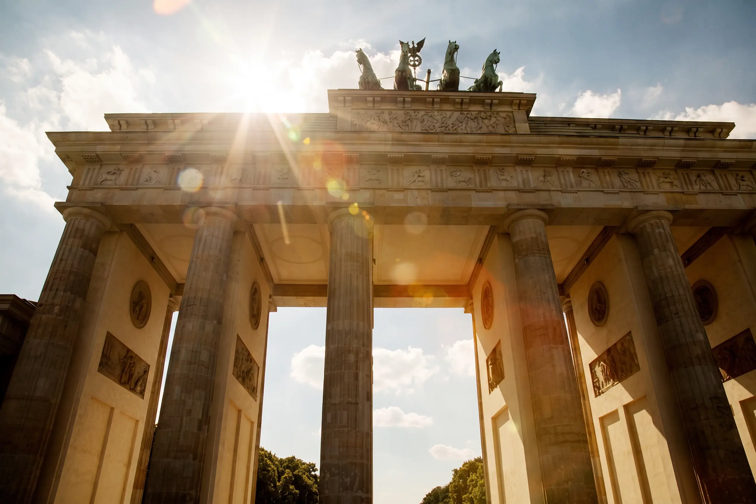 day-hero-brandenburg-gate-with-sunflare-and-clouds-berlin-germany.webp