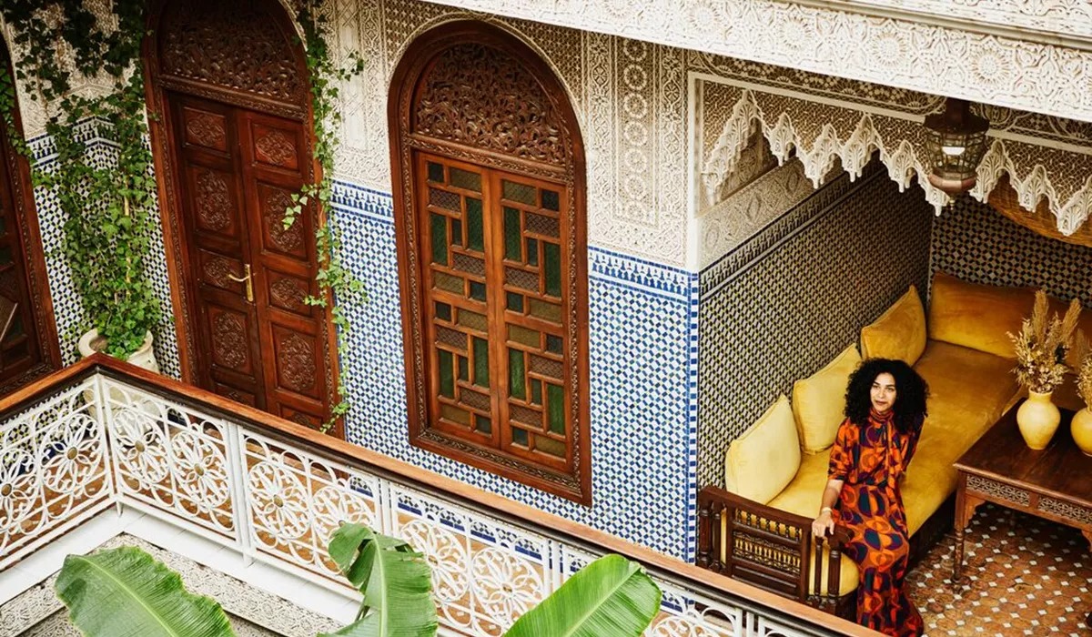 Woman in a colorful dress sitting in a traditional Moroccan-style courtyard