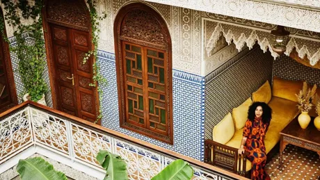 Woman in a colorful dress sitting in a traditional Moroccan-style courtyard