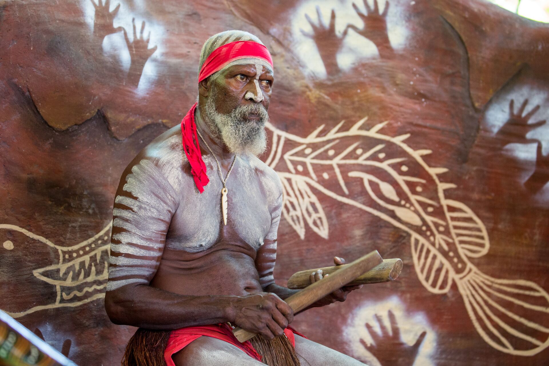 Aboriginal man sitting in front of traditional artwork in Australia