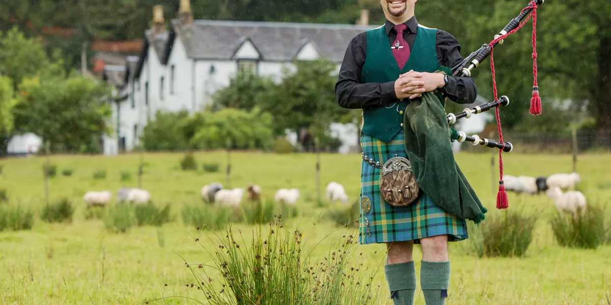 A man in traditional Scottish clothing with bagpipes