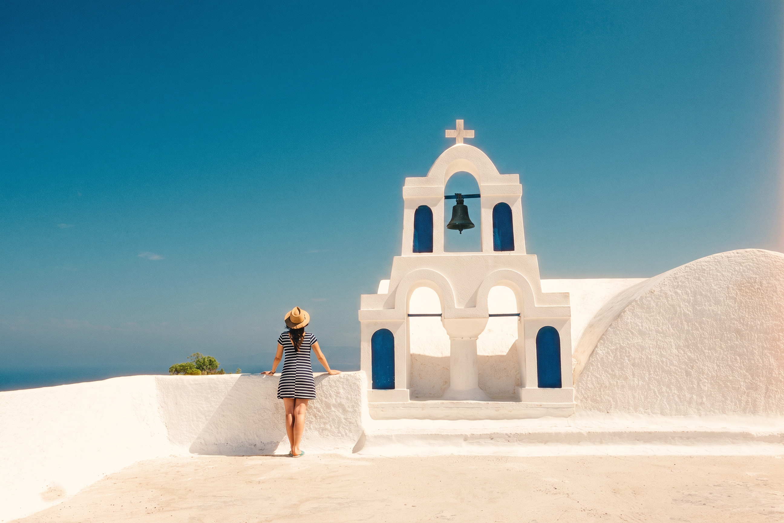 day-hero-woman-standing-next-to-bell-tower-santorini-greece-668762579.webp