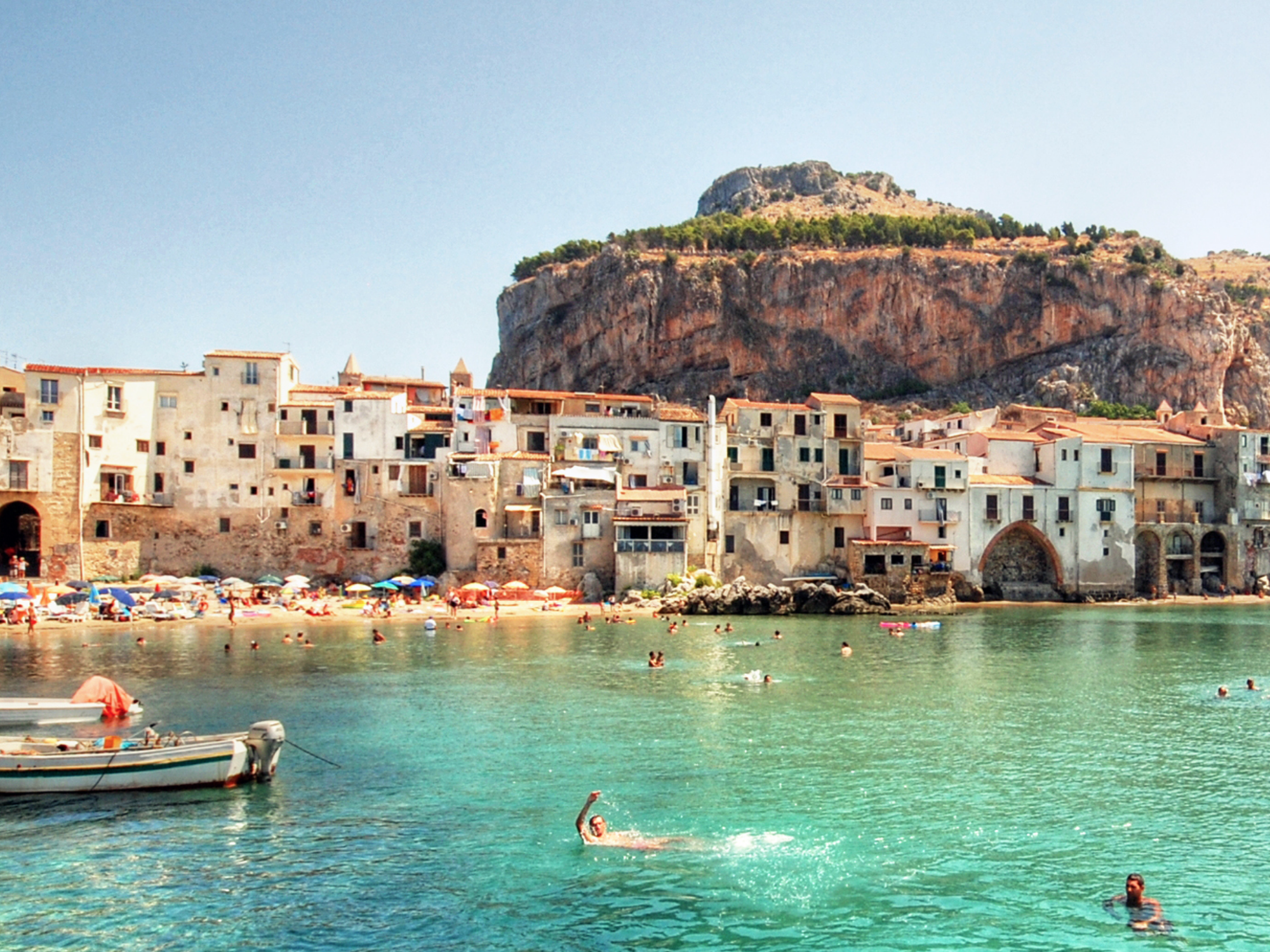 Italian coast with azure water and people swimming in it
