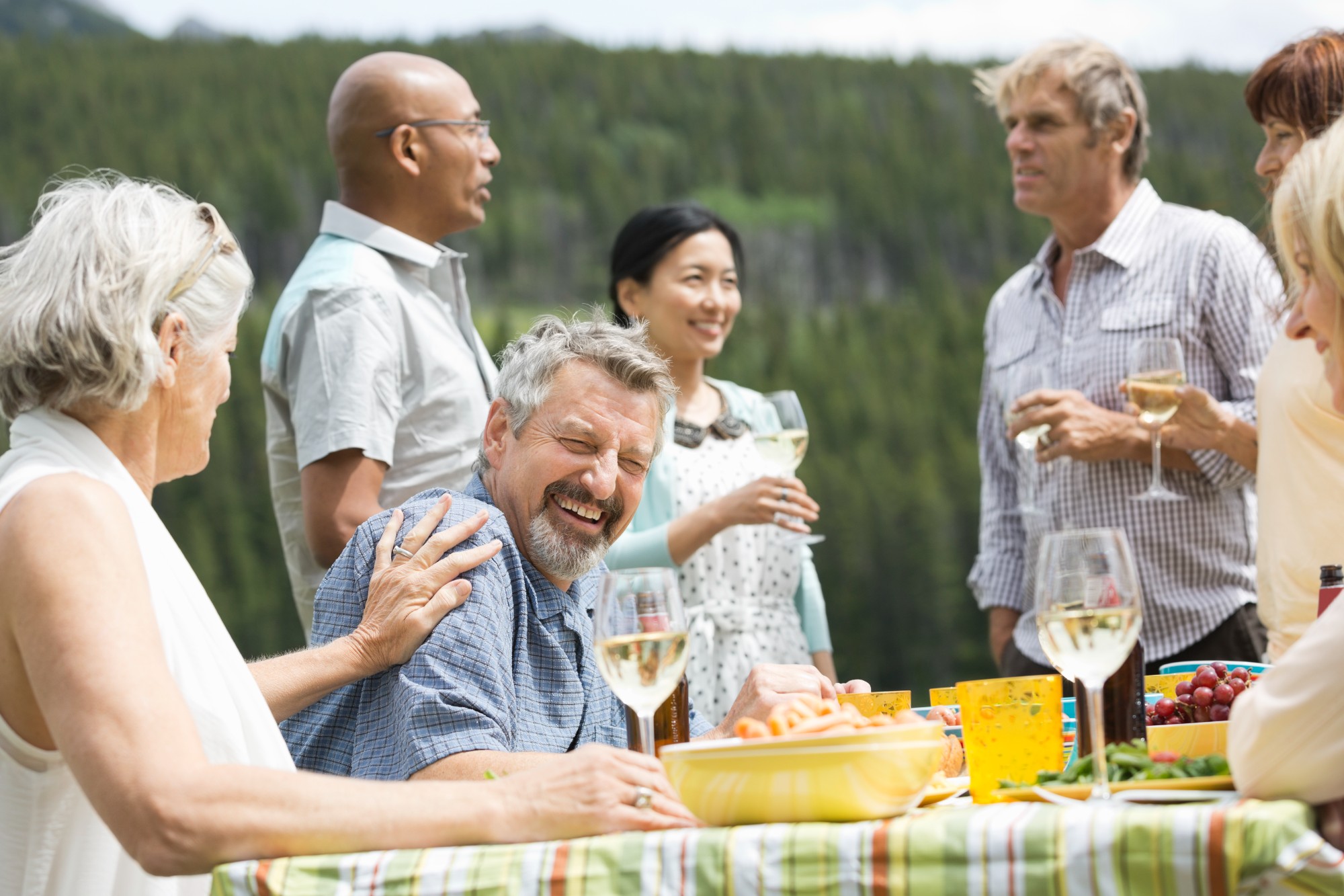 Tourists dining and drinking wine outside in green scenery 