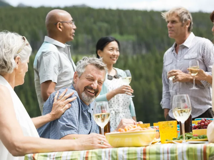 Tourists dining and drinking wine outside in green scenery