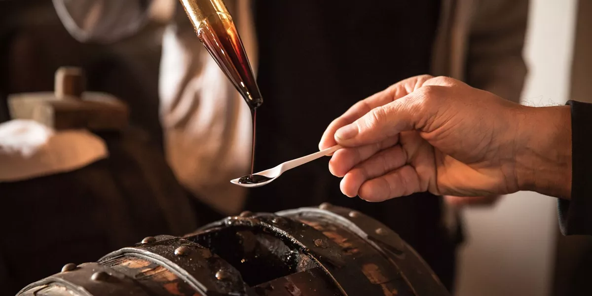 Large Midsection Of Woman Pouring Vinegar On Spoon Held By Friend 1167789543