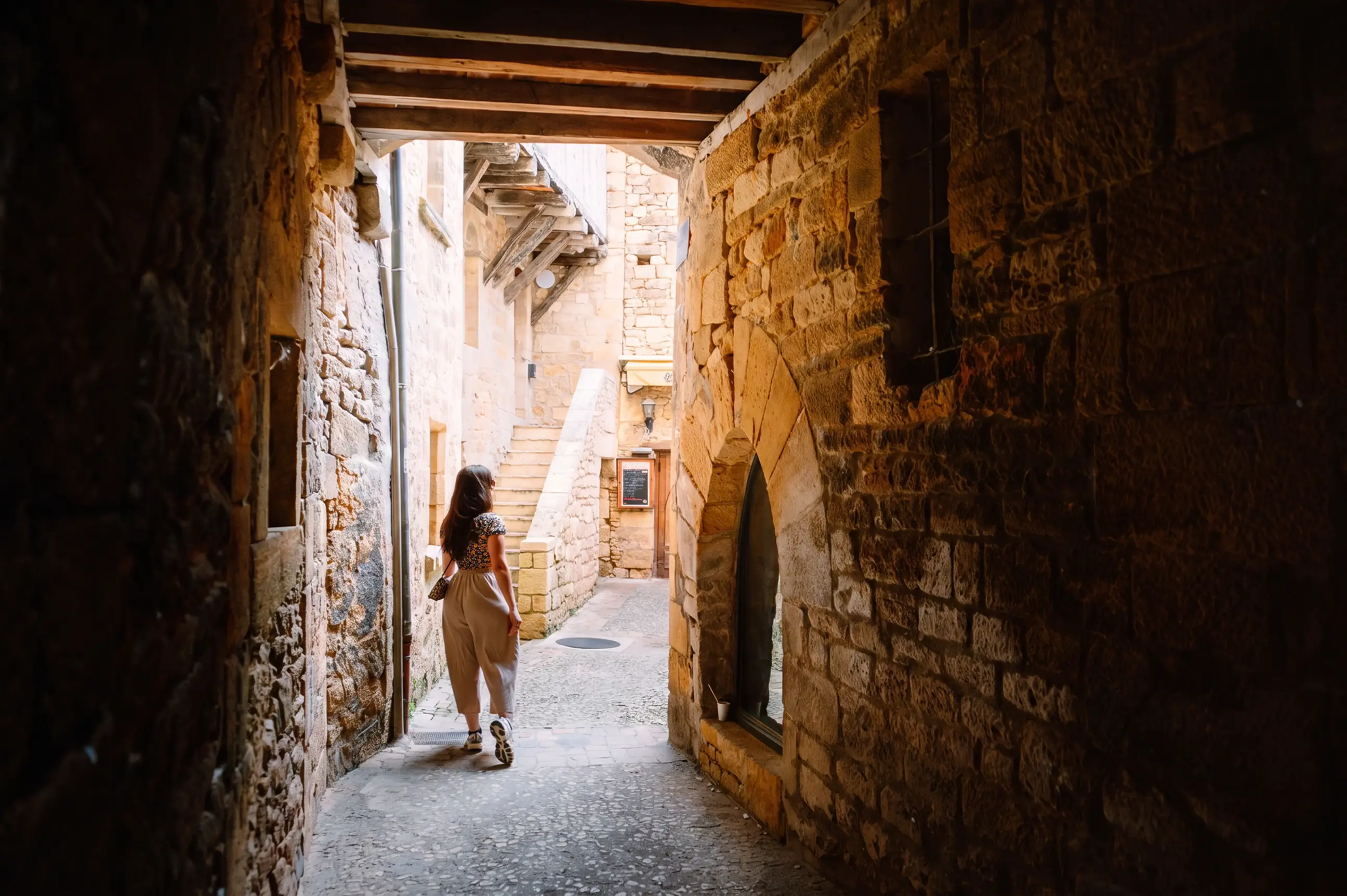 day-hero-woman-exploring-a-medieval-alley-in-sarlat-la-cane-da-france.webp