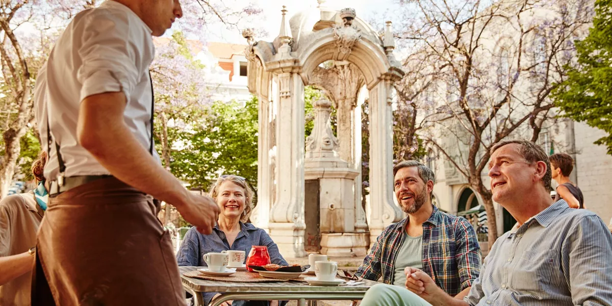 Guests talking to a waiter while in Lisbon, Portugal