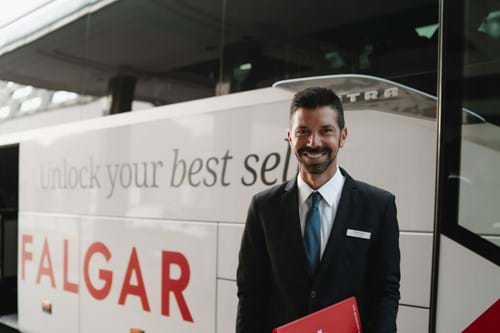 Tour Director smiling and stood infront of a Trafalgar coach