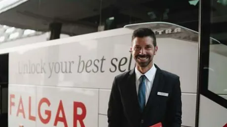 Tour Director smiling and stood infront of a Trafalgar coach