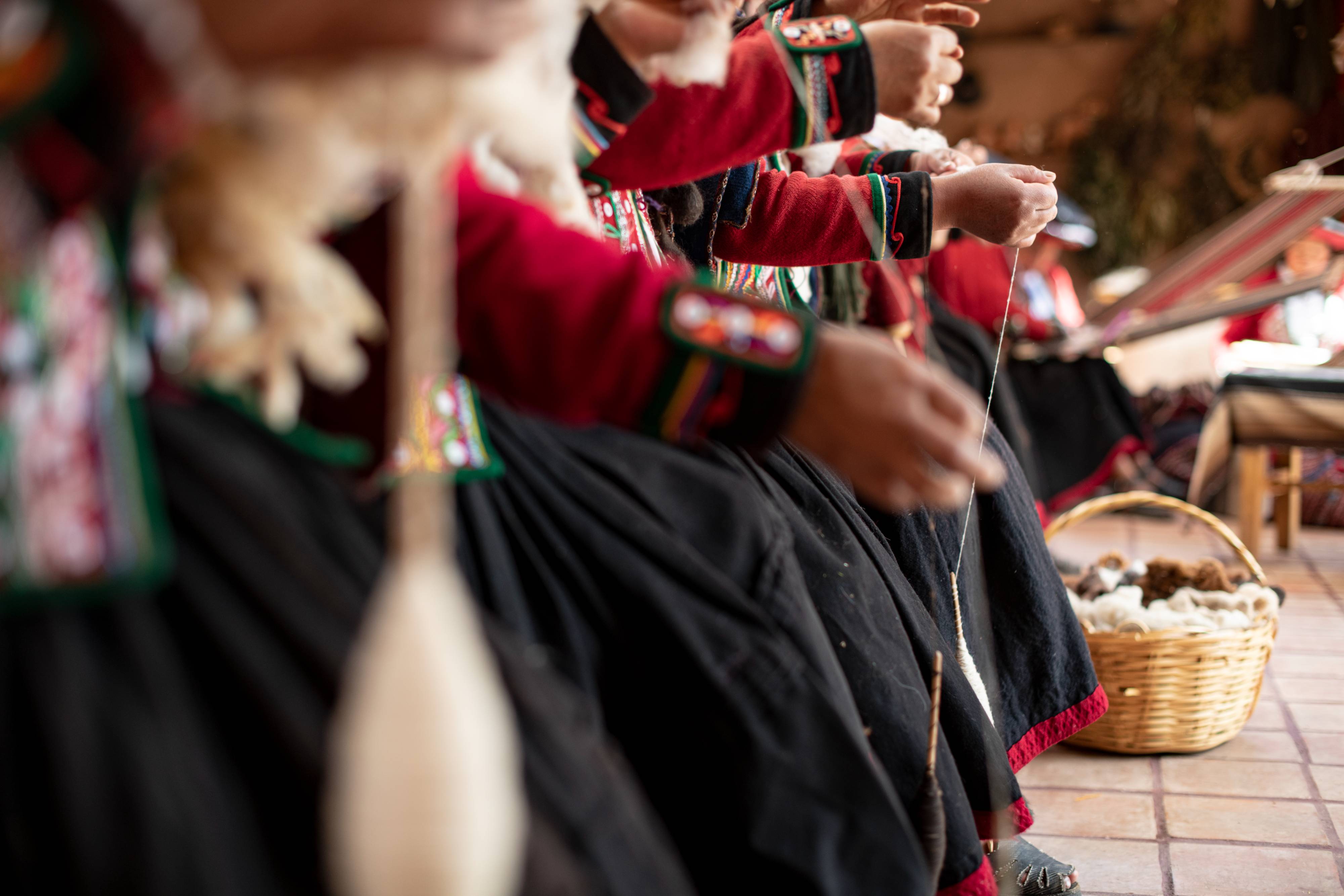Hands of women in traditional dresses knitting 