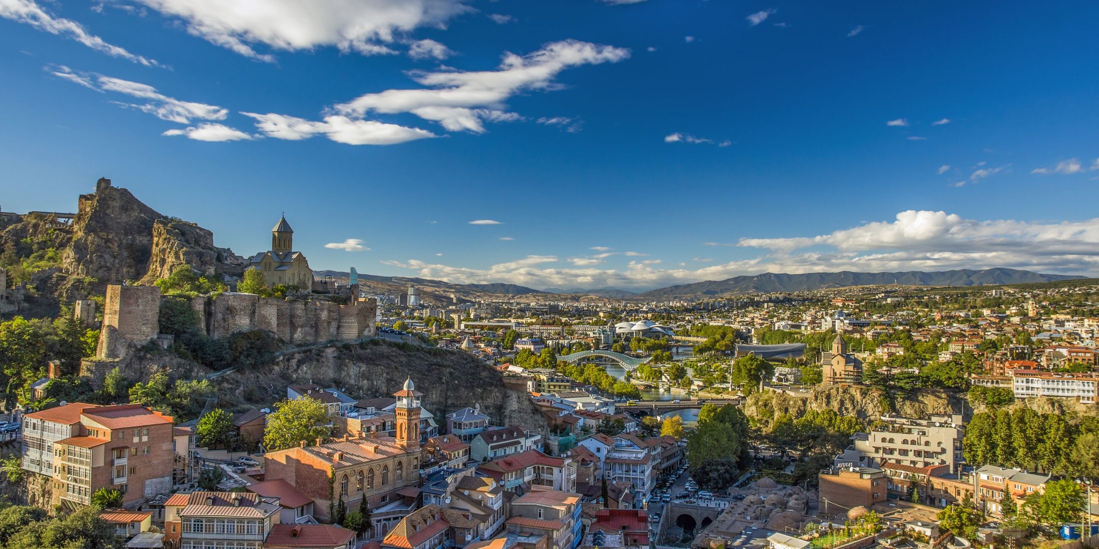 Panorama of Old Town of Tibilisi in Georgia including ruins on a hill and mountains in the background