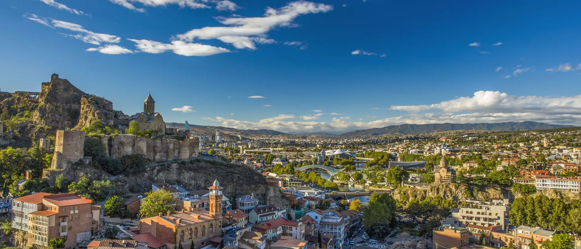 Panorama of Old Town of Tibilisi in Georgia including ruins on a hill and mountains in the background