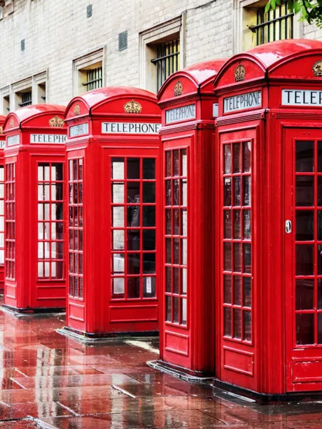 Row of traditional red phone boxes on a street of Covent Garden in London, England