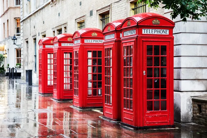 Row of traditional red phone boxes on a street of Covent Garden in London, England