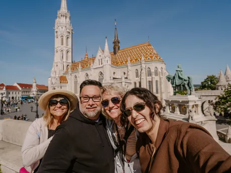 A group of smiling guests take their picture in front of a cathedral in Budapest