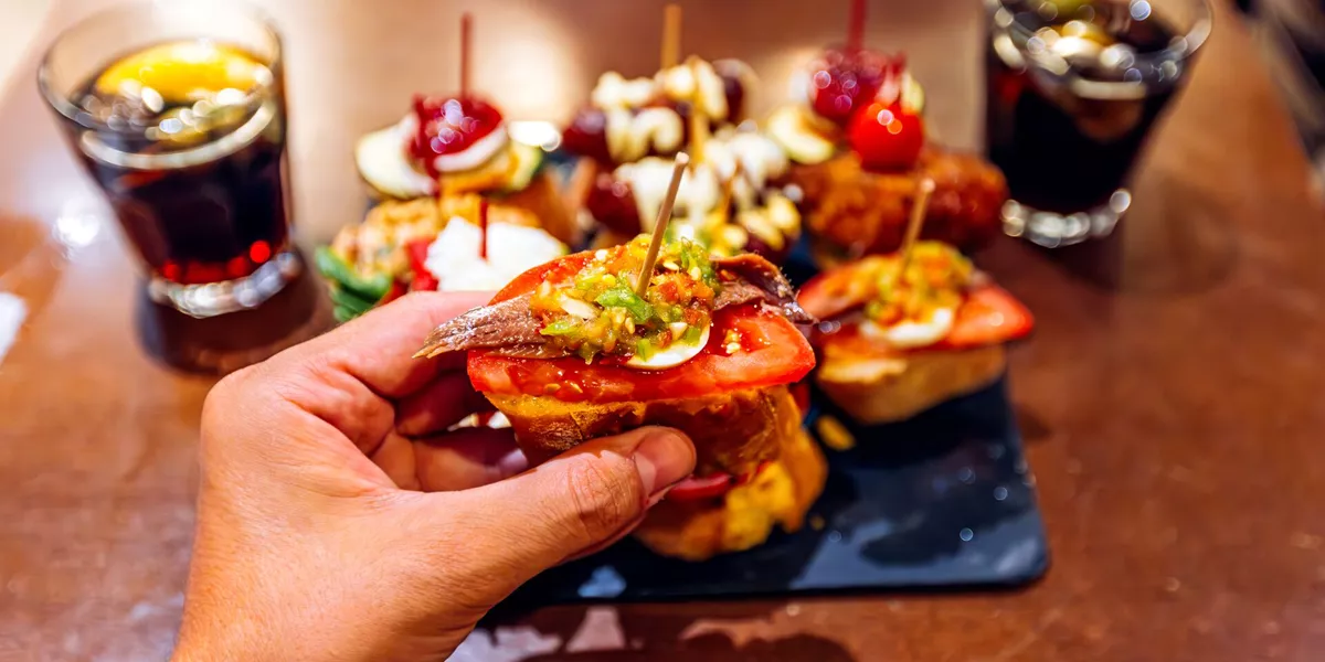 Man eating anchovy pincho at Spanish tapas bar in Barcelona, Spain