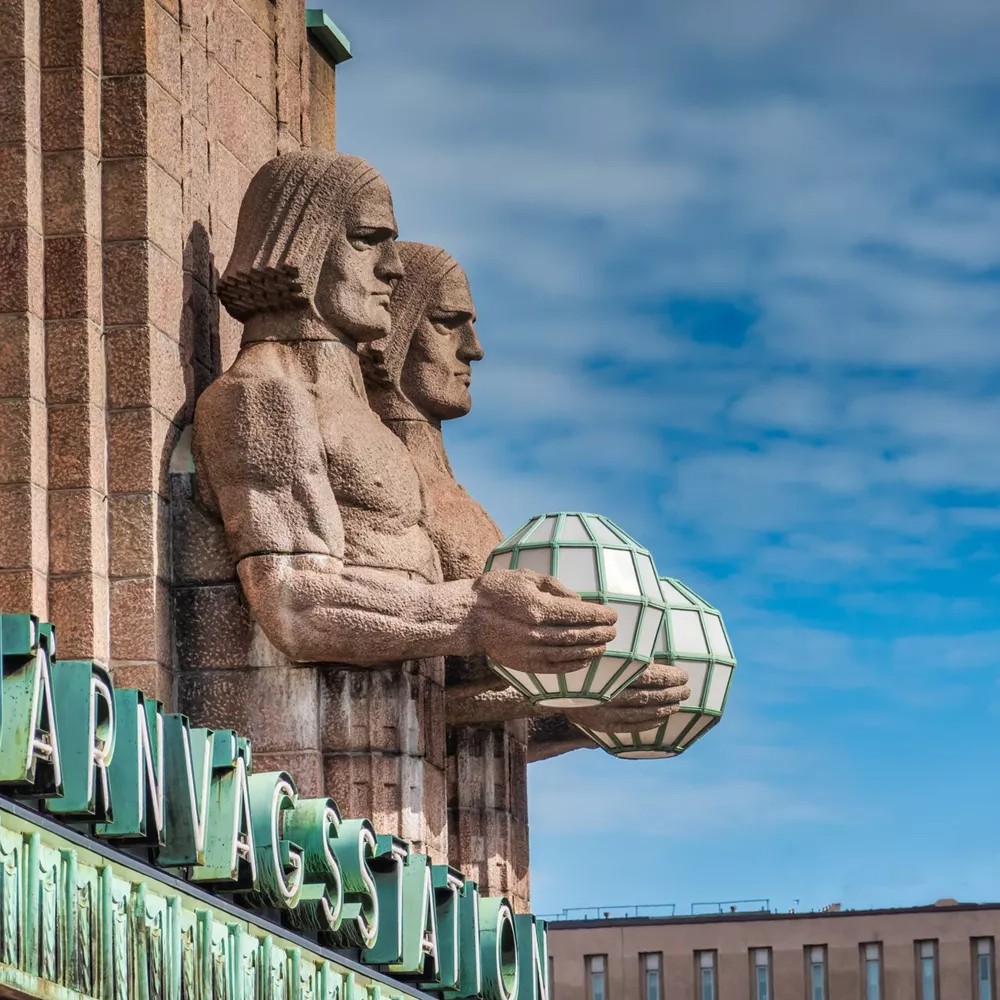 Stone Sculptures attached to railway station in Helsinki holding metal globes, Finland