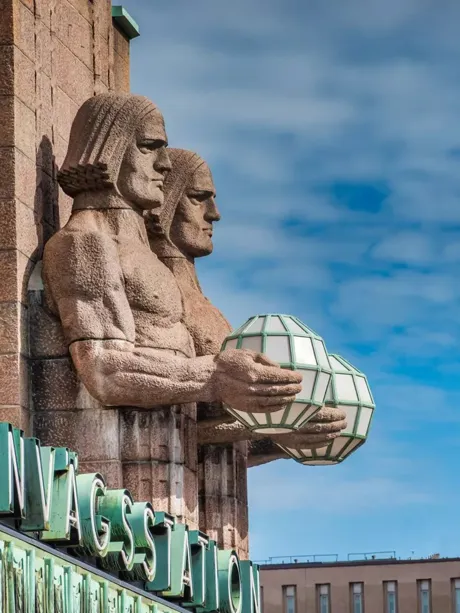 Stone Sculptures attached to railway station in Helsinki holding metal globes, Finland