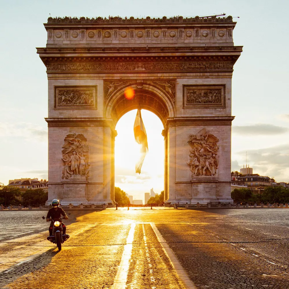 Sun beams coming through Arc De Triomphe in Paris, France