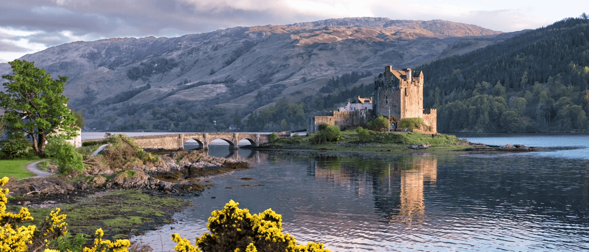 View of Eileen castle over the water with mountains in the background
