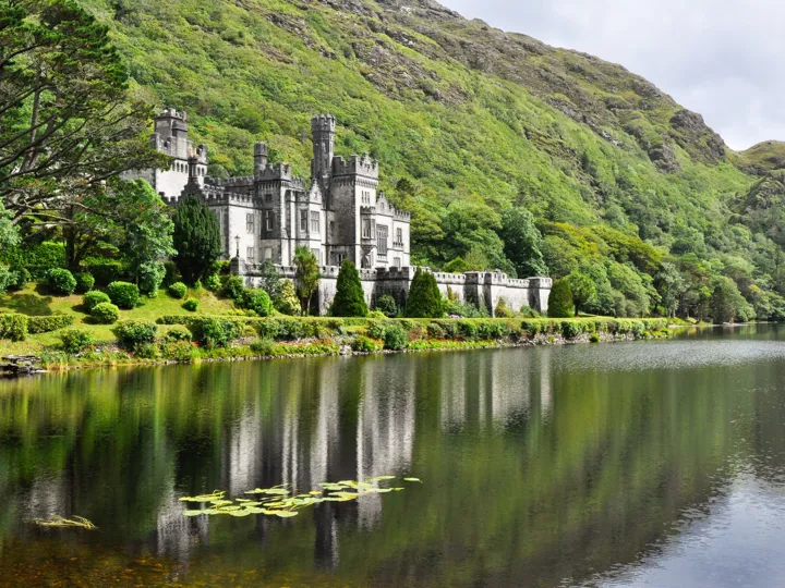 View From Water Of Kylemore Abbey Near Trees In Ireland