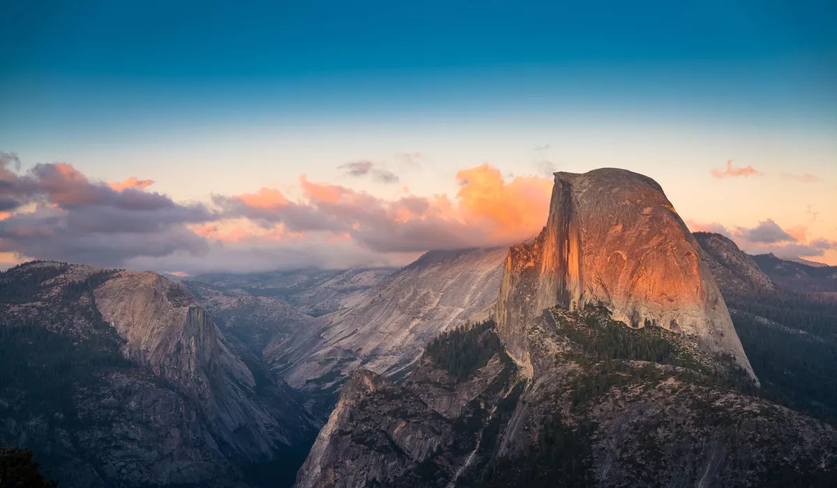 Sunset view of Half Dome in Yosemite National Park with clouds and granite cliffs