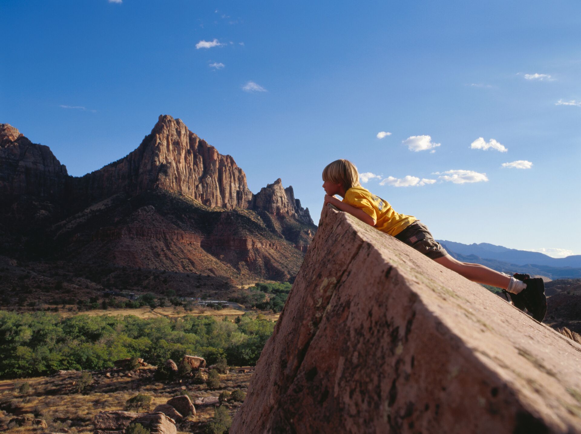 Boy peering over a rock in Monument National Park in Arizona, United States