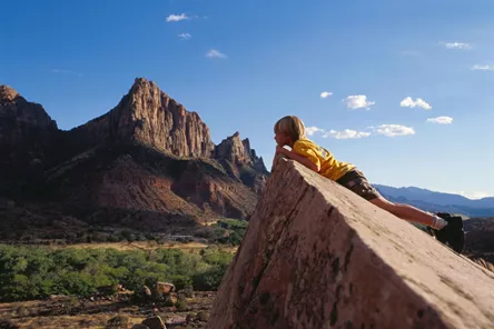 Boy peering over a rock in Monument National Park in Arizona, United States