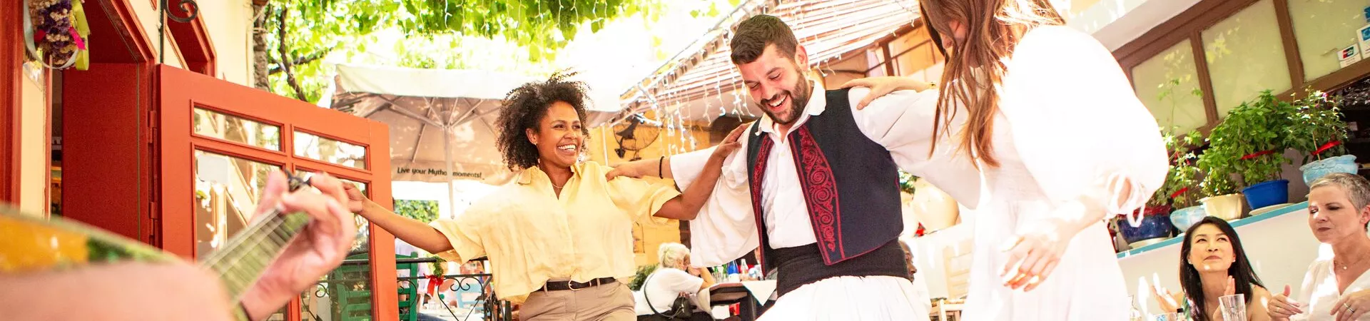 Guests in Greece dancing and enjoying a traditional meal