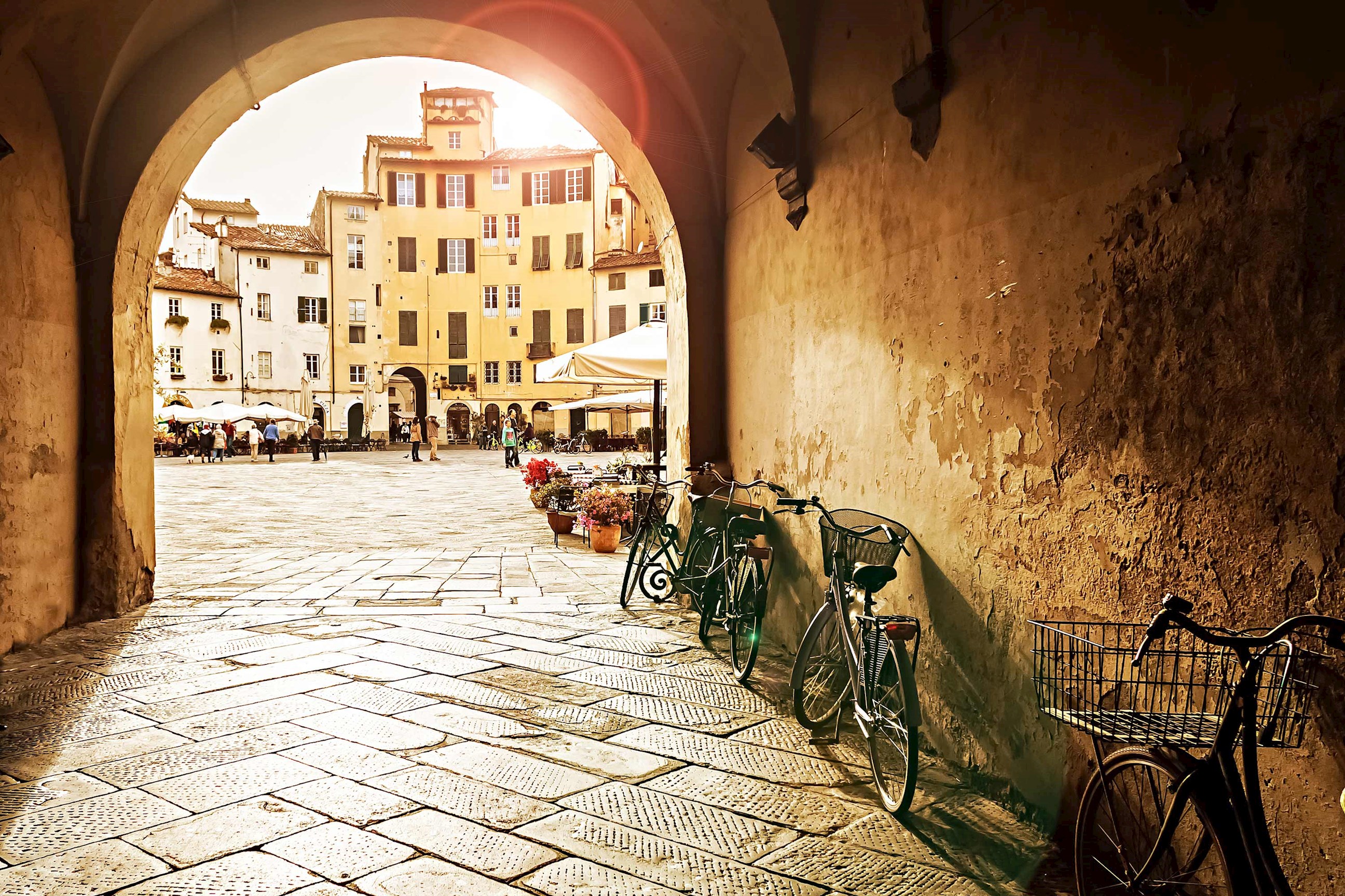 Archway view of Piazza dell’Anfiteatro with bikes leaning on wall in Lucca