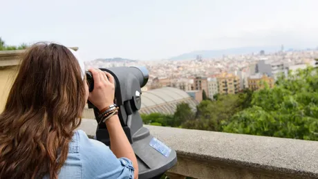 A woman watching the city through binoculars