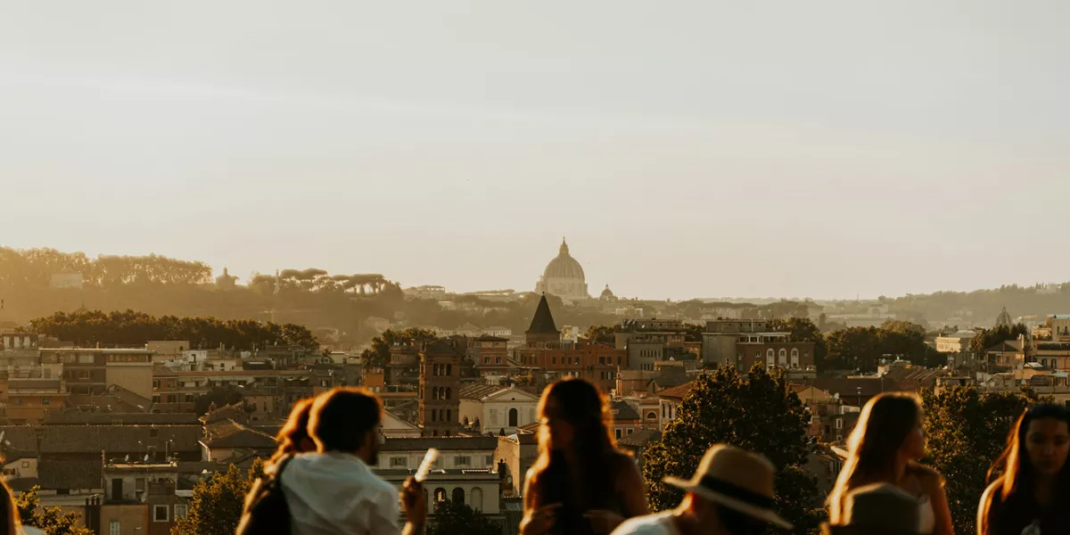 A group of guests photographed looking out at a view of the rooftops of an Italian city.