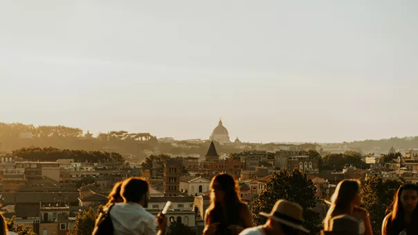 A group of guests photographed looking out at a view of the rooftops of an Italian city.