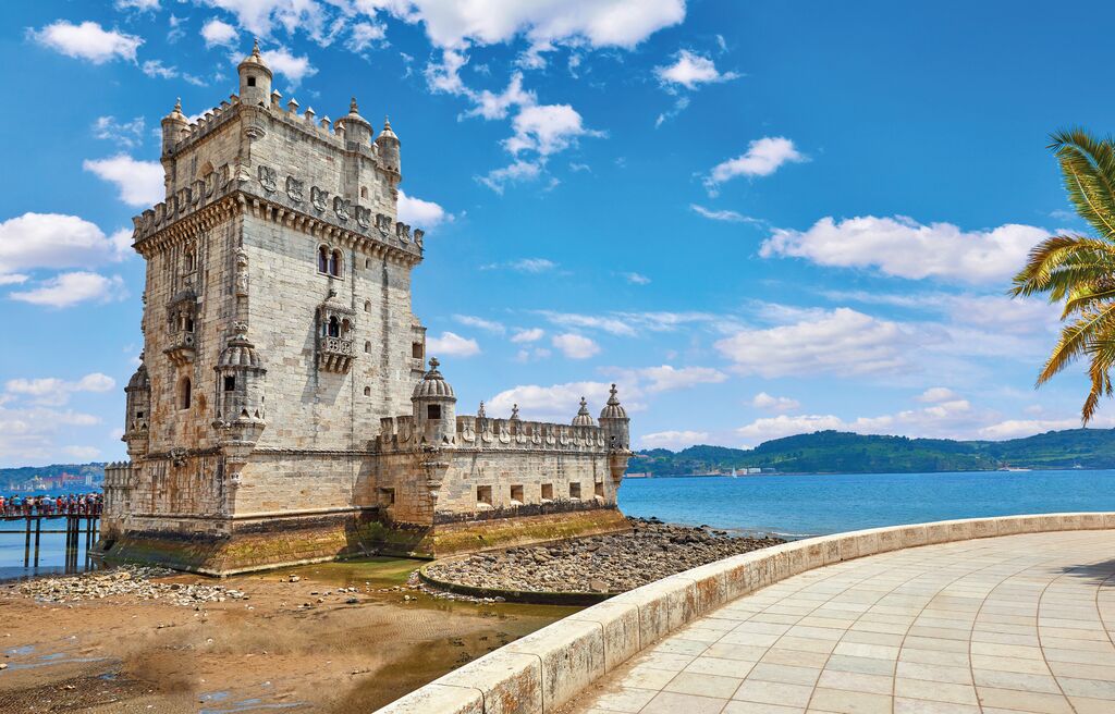 Tower Belem at Coast Embankment Alley with palm tree in Lisbon, Portugal