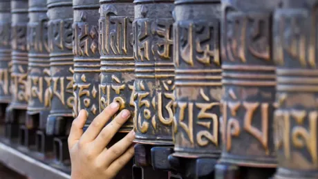 A hand touching the Prayer Wheels in Kathmandu, Nepal