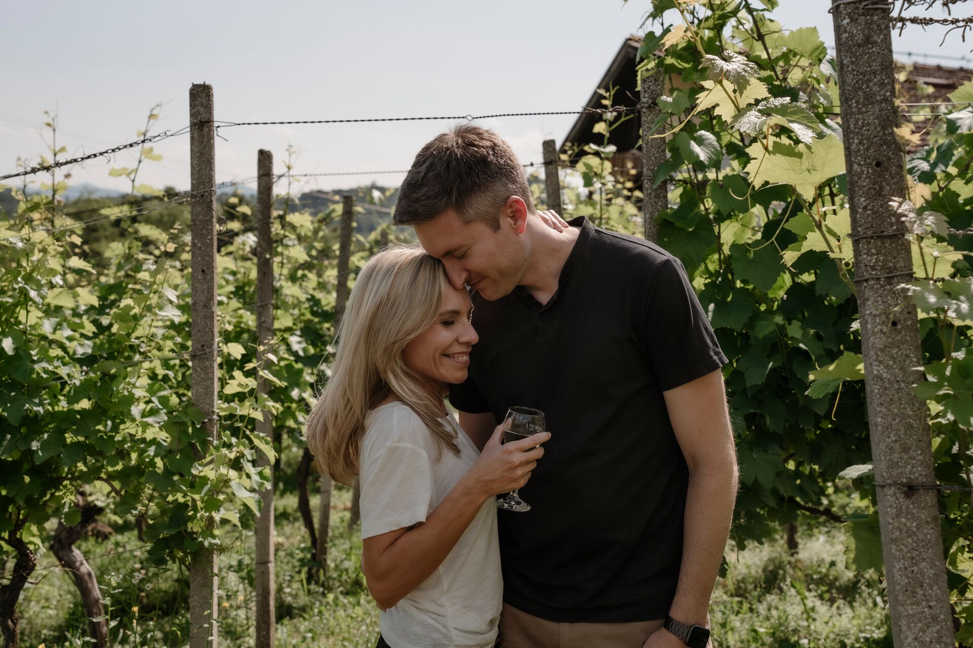 A couple pose in a vineyard