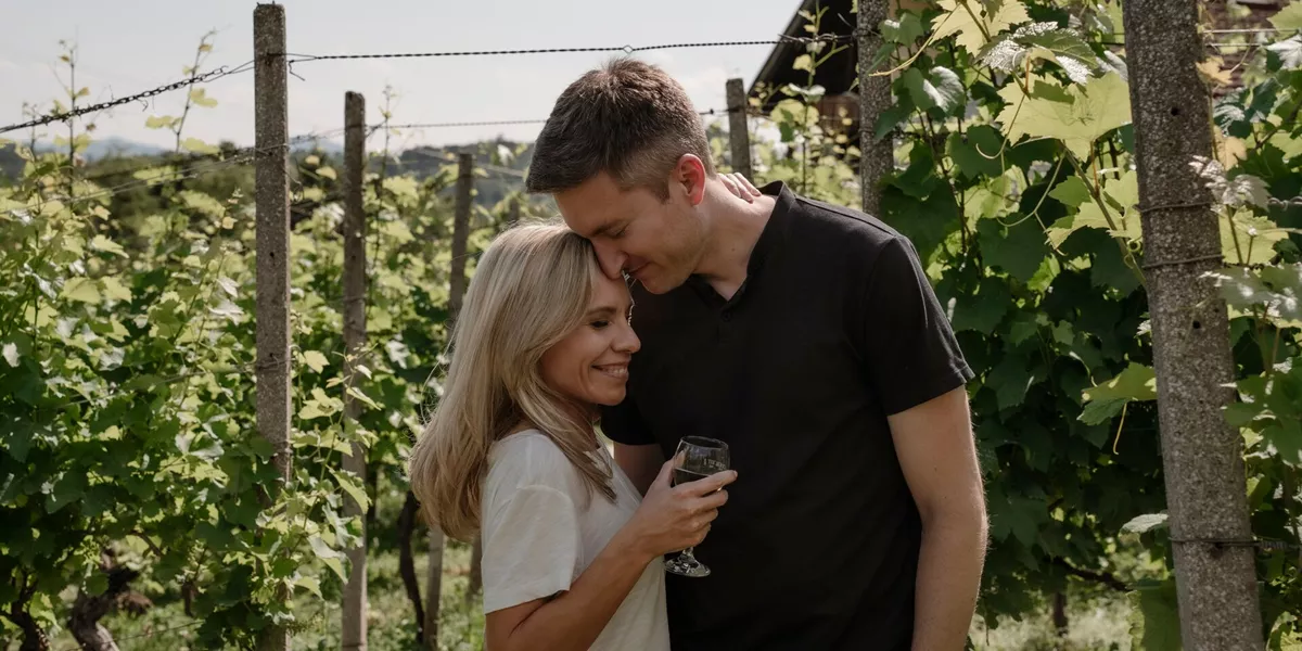 A couple pose in a vineyard