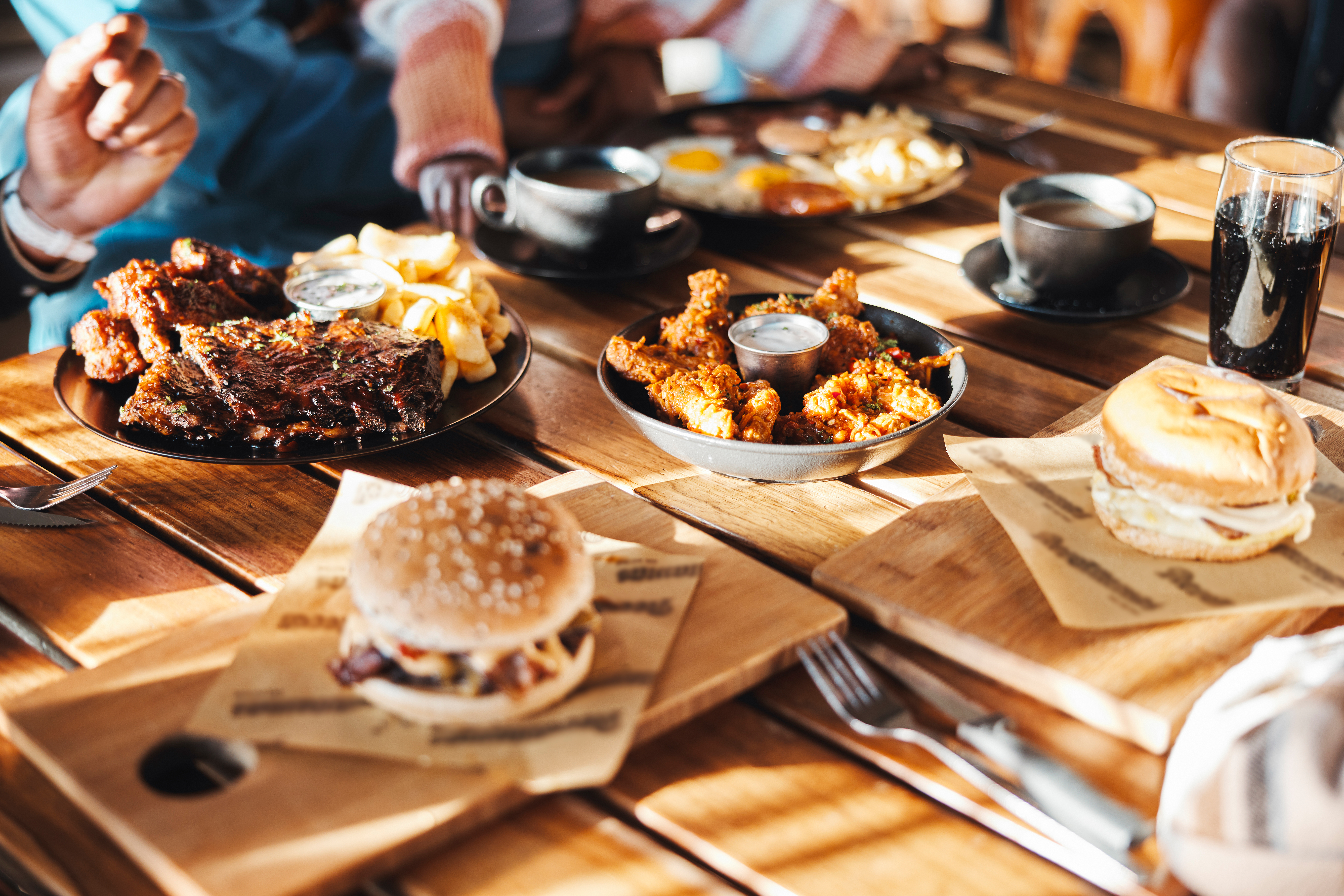 A variety of fast foods such as burgers, chicken wings and ribs laid out on a restaurant table