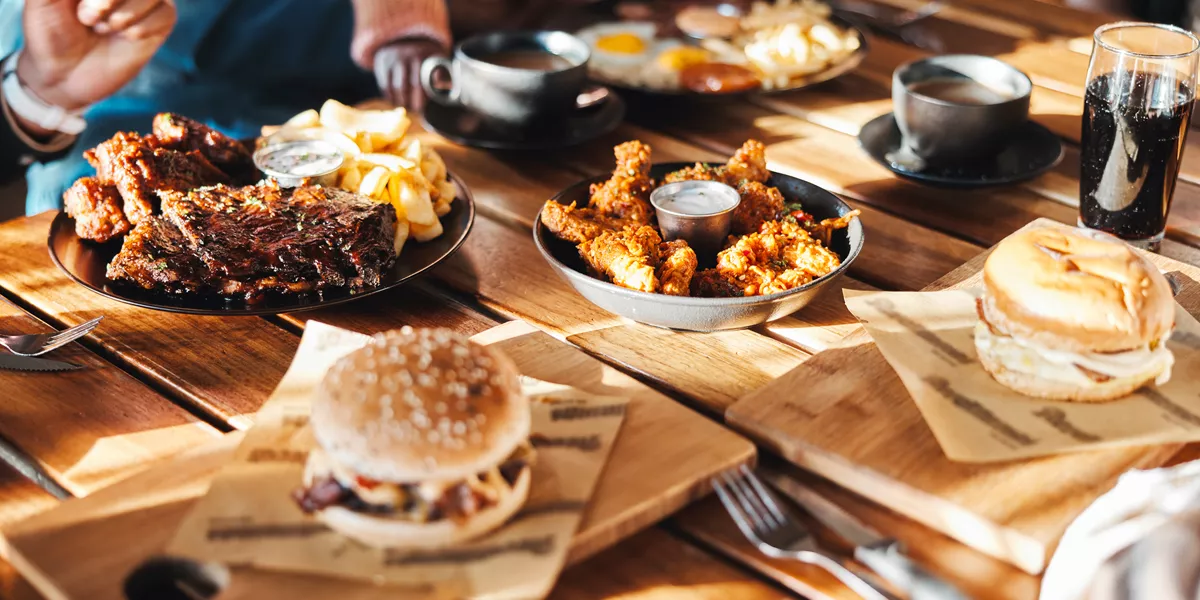 A variety of fast foods such as burgers, chicken wings and ribs laid out on a restaurant table