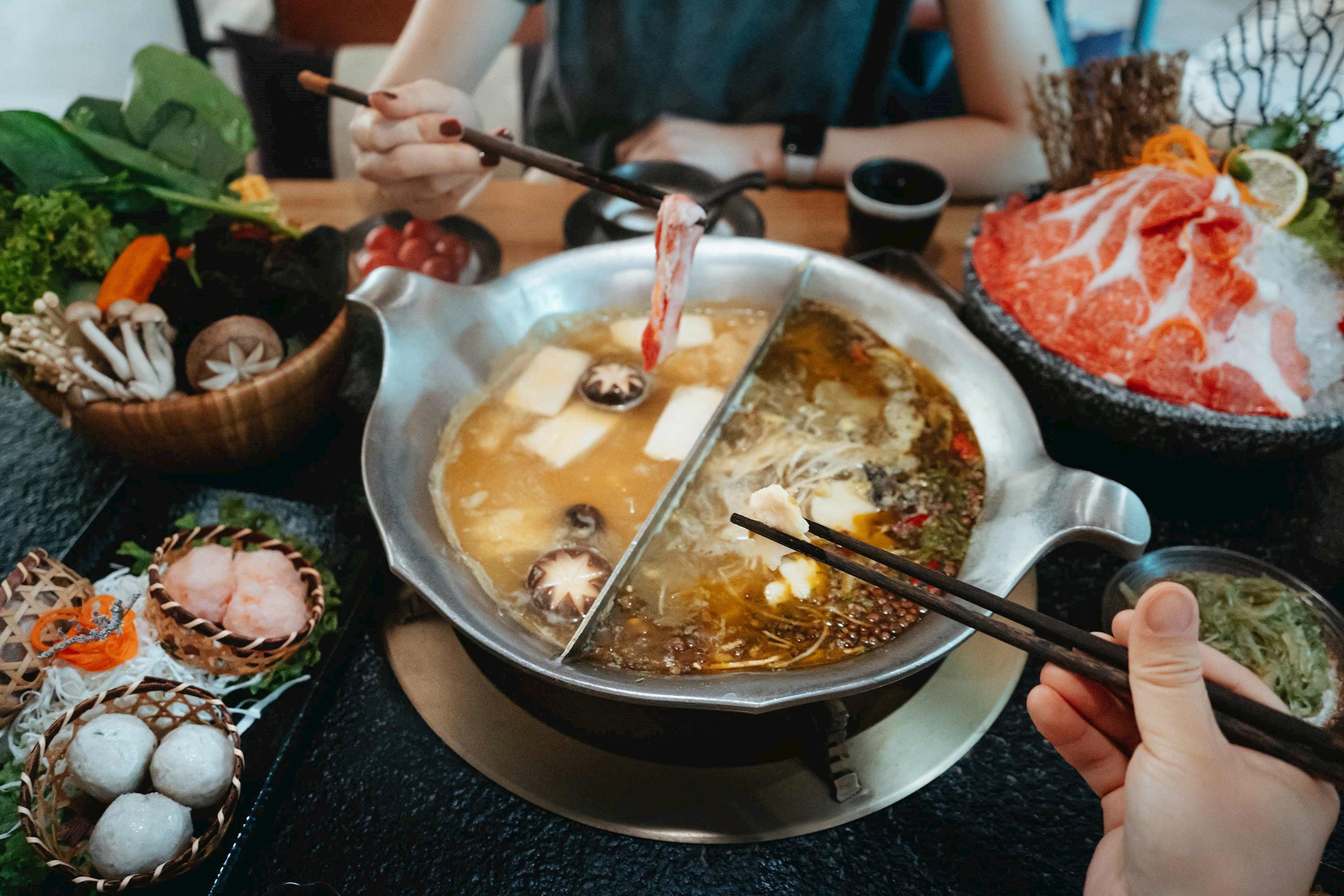 Close-up of hot pot with assorted vegetables, mushrooms and sliced meat