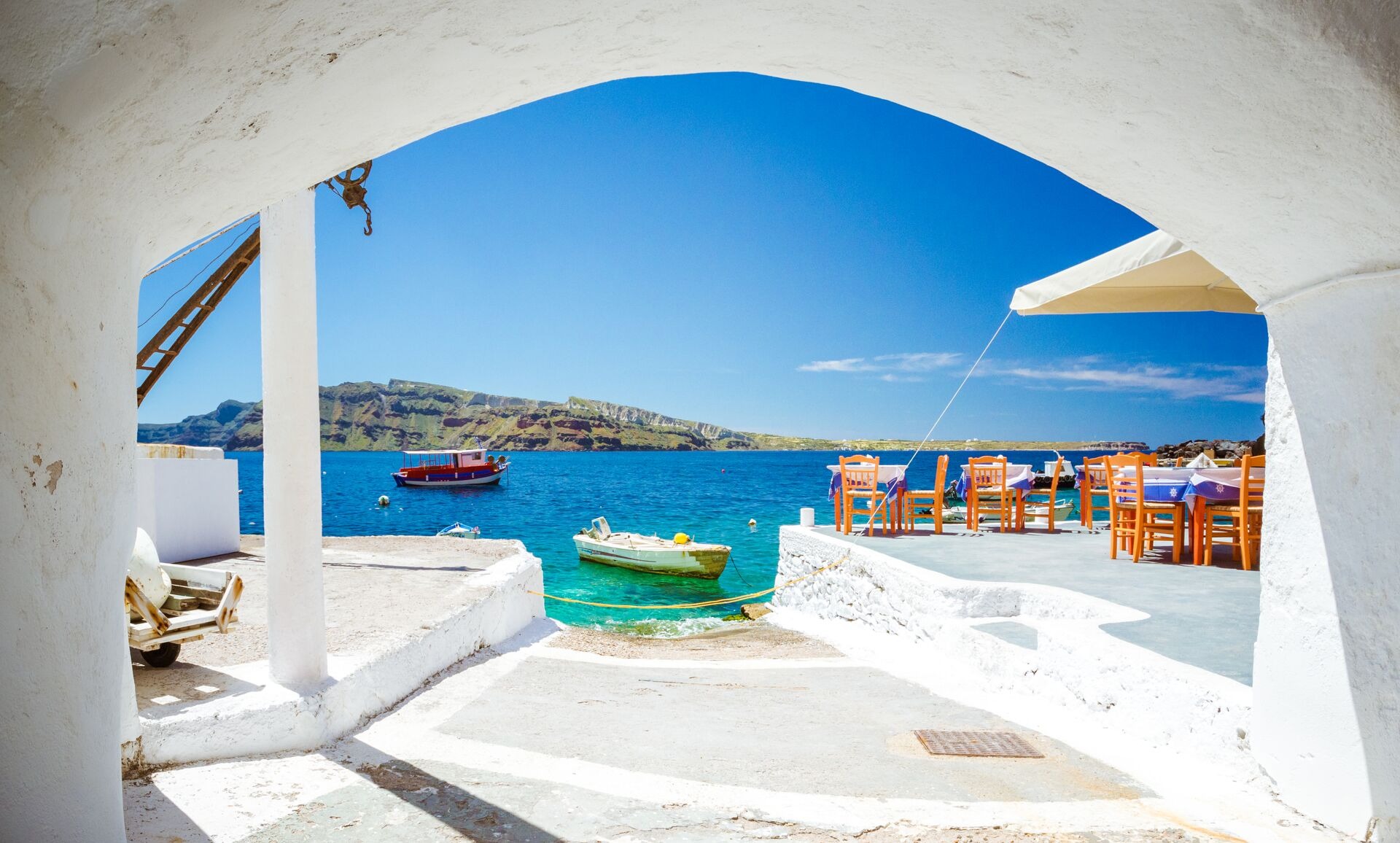The Old Harbor Of Ammoudi Under The Famous Village Of Oia At Santorini Greece Through A Frame Of An Old Arched Building