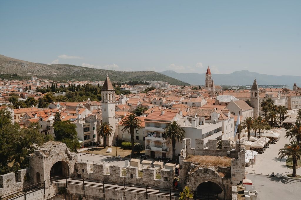 Trogir old town in Croatia with red rooftops, stone towers, and palm trees