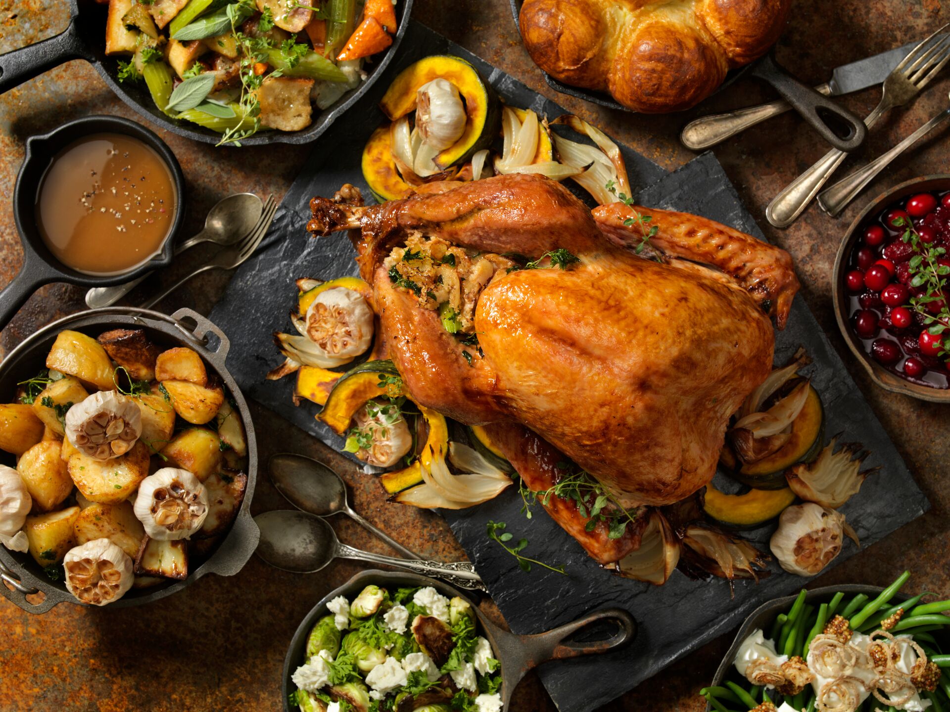 Roast turkey dinner with sides of salads, bread and roasted potatoes