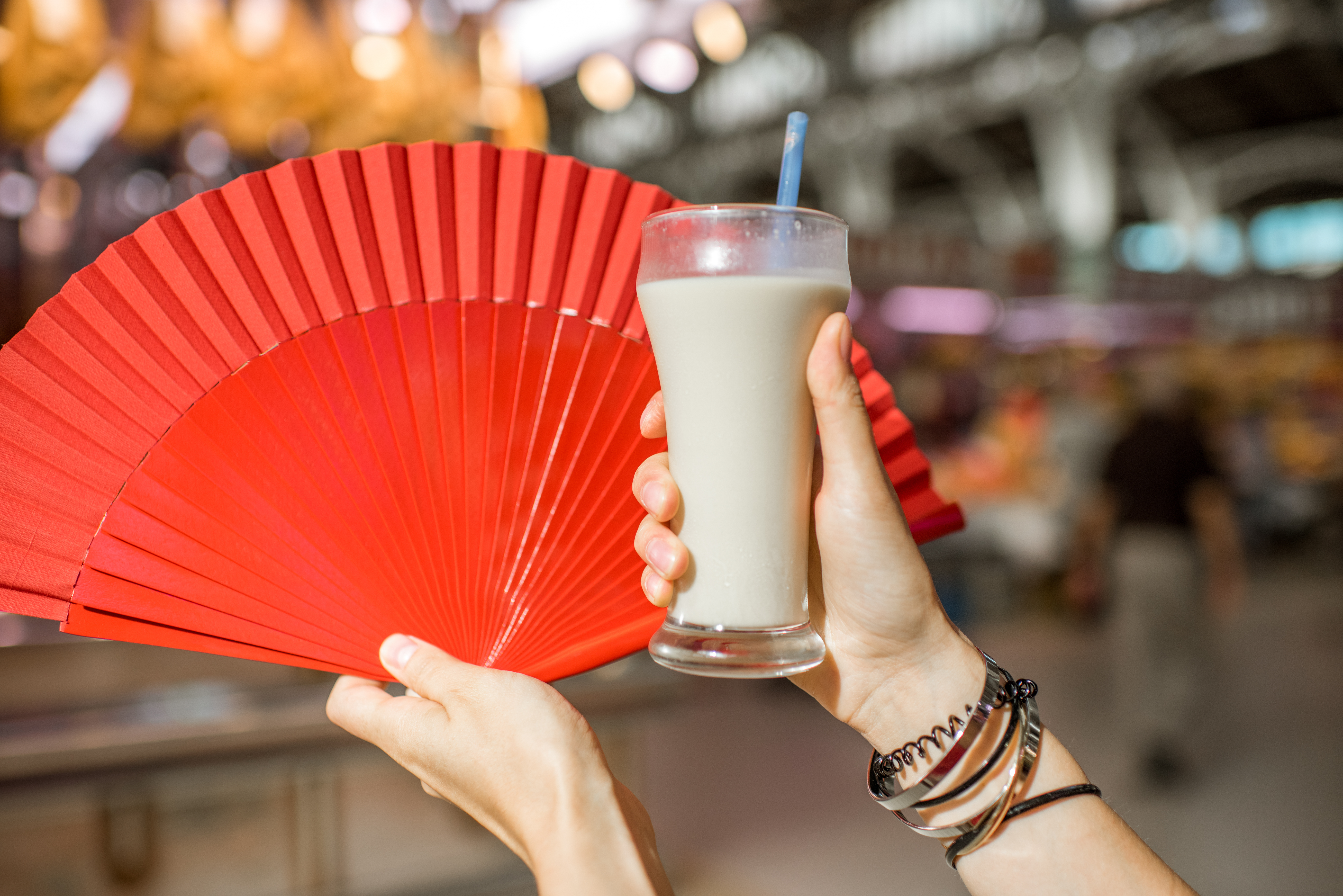 Hands holding Horchata Traditional Spanish Drink and a red fan