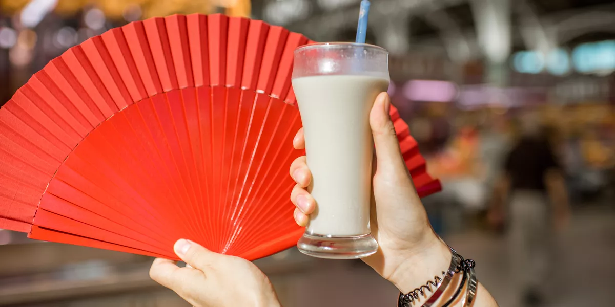 Hands holding Horchata Traditional Spanish Drink and a red fan