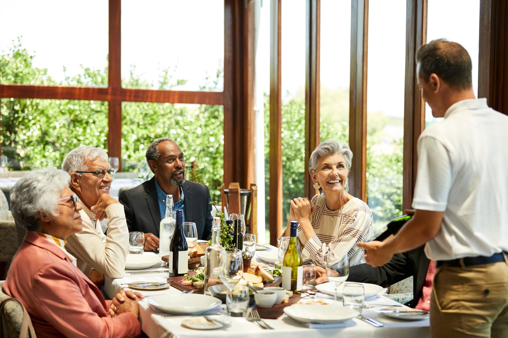 Sommelier talking to senior friends in restaurant 